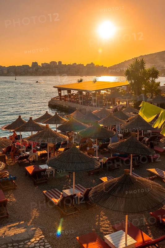 Beautiful resort with umbrellas and palm trees by the sea at sunset in Sarande or Saranda on the Albanian riviera, Albania, Europe