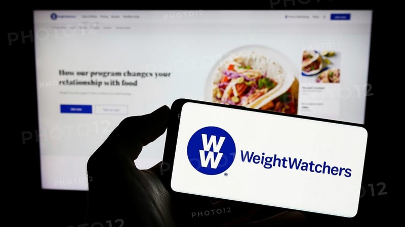 Stuttgart, Germany, 03-19-2023: Person holding cellphone with logo of WW International Inc. (Weight Watchers) on screen in front of business webpage. Focus on phone display, Europe
