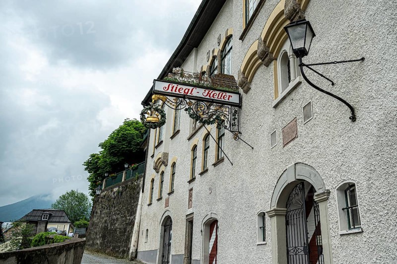 A traditional pub sign on a white wall of a European building on a cloudy day, Salzburg, Austria, Europe