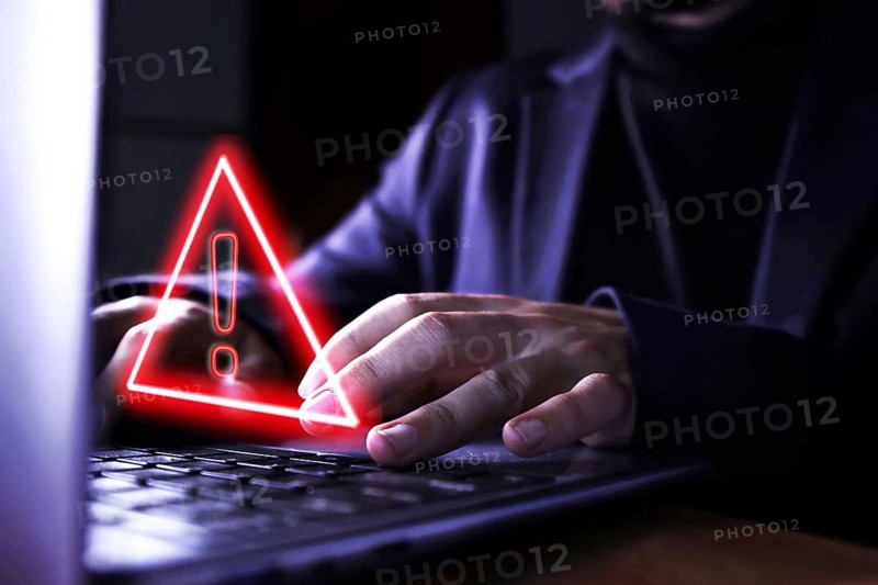 Hands of a businessman using the computer on fraudulent pages. Caution symbol of danger of hackers and malicious viruses when surfing the Internet. Concept of control and technological security.
