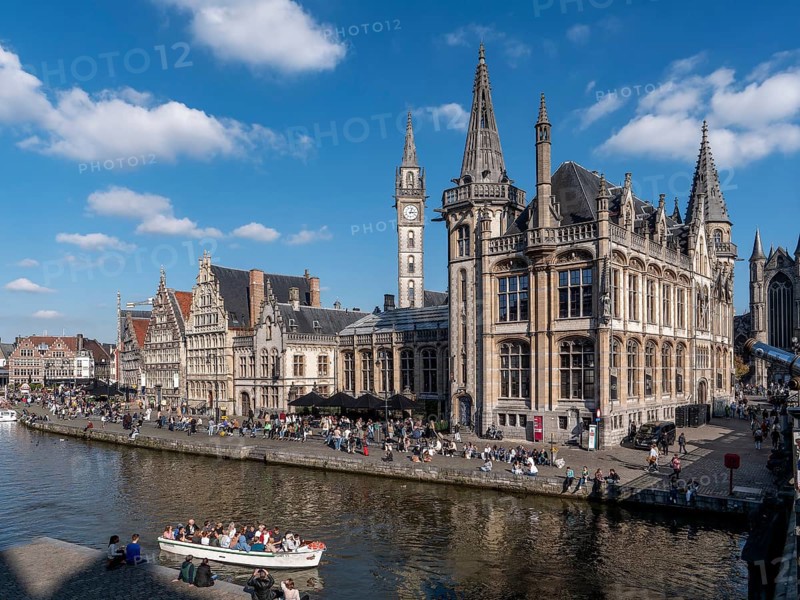 Medieval old town centre with historic buildings former post office building, St. Nicholas Church, Sint-Niklaaskerk and tourists in the tourist boat for the canal cruise on the river Leie, Ghent, East Flanders, Belgium, Europe