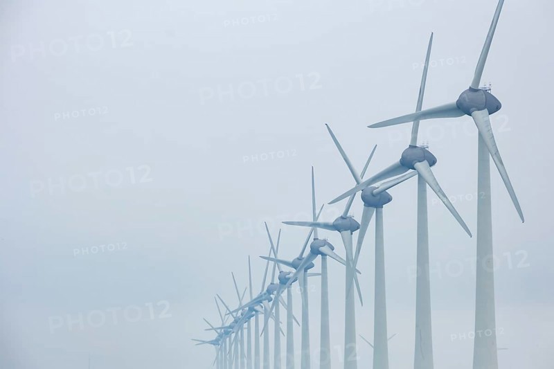 Wind turbines in a row on the coast in the mist and fog