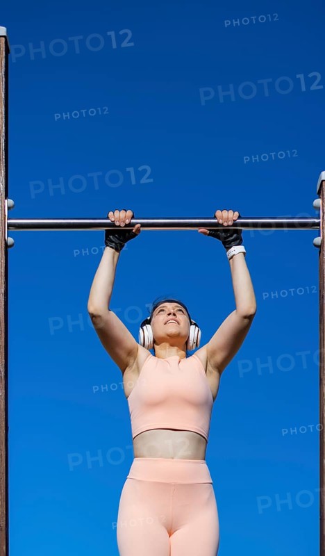 Young girl doing calisthenics exercise on bars outdoors. pull-up exercise
