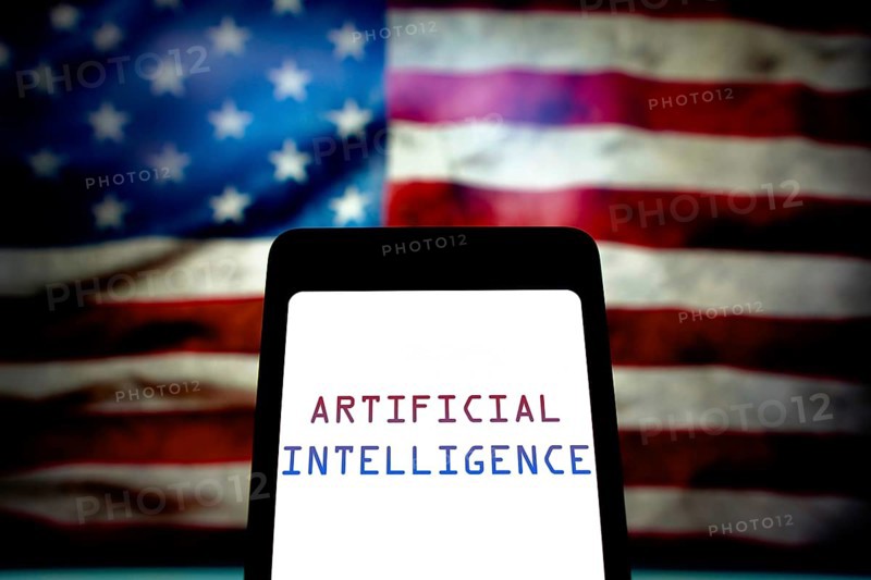 May 21, 2024, Brazil. In this photo illustration, the Artificial Intelligence (AI) text is displayed on a smartphone screen and in the background, the flag of the United States. The United States government has issued an executive order that aims to control and regulate the risks posed by artificial intelligence technologies