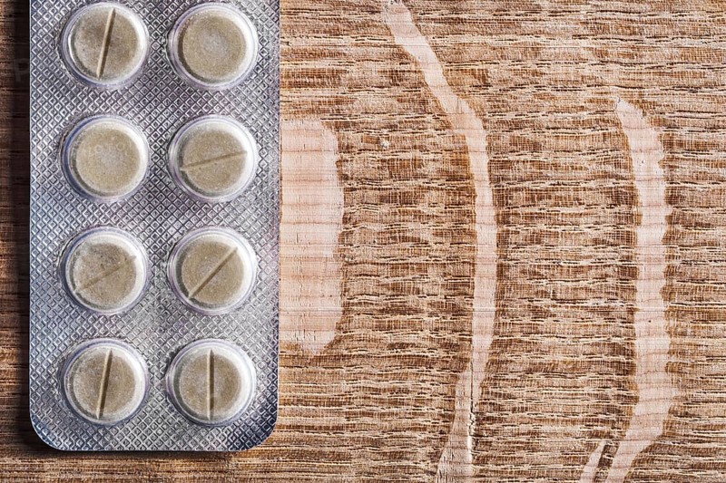 Blister pack with pills on vintage wooden board with organised copyspace medical concept