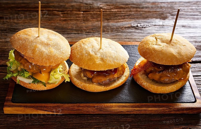 Burger in a row on a slate board and wood table