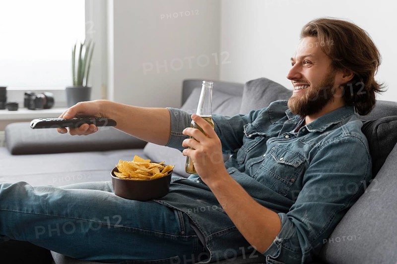 Medium shot man with drink watching tv