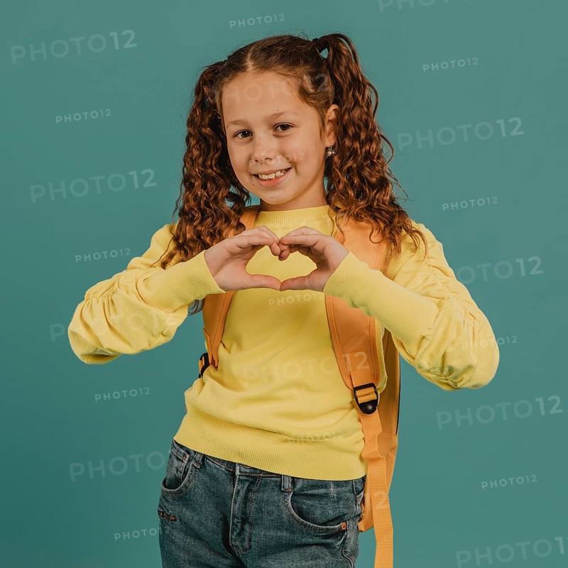School girl with yellow shirt making heart shape