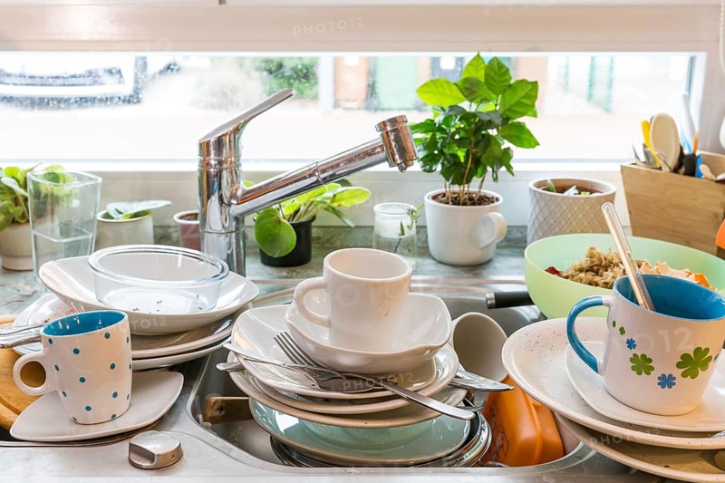 Messy kitchen counter with pile of dirty dishes in sink - Compulsive Hoarding Syndrome