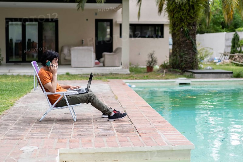 Latin man working on his laptop in the pool