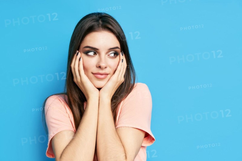 Portrait of shy happy excited female on blue background with copy space. People emotions, facial expression concept