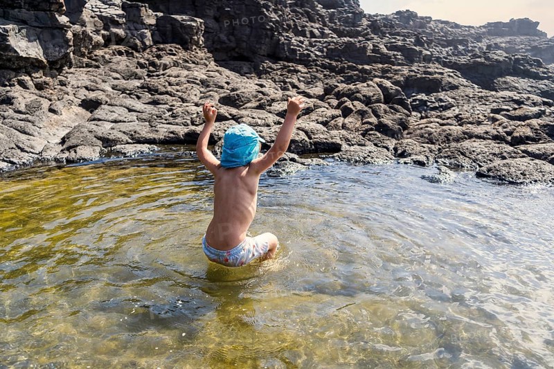 Small boy cheerfully jumping in Charcones natural pools in Lanzarote, Canary Islands, Spain, Europe