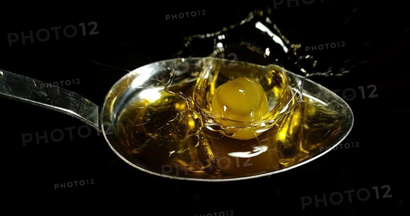 Green Olive, Olea europaea, Falling in a Spoon against Black Background