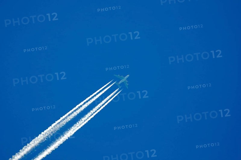 Four-engine jet with condensation trails in the blue sky