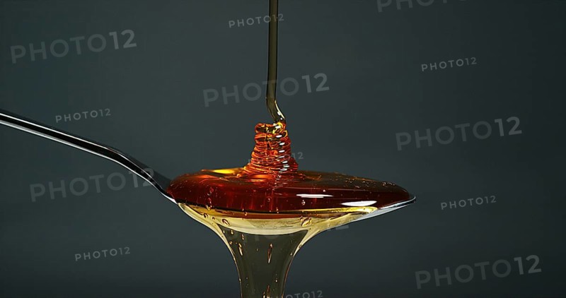 Honey Flowing in a spoon against Black Background