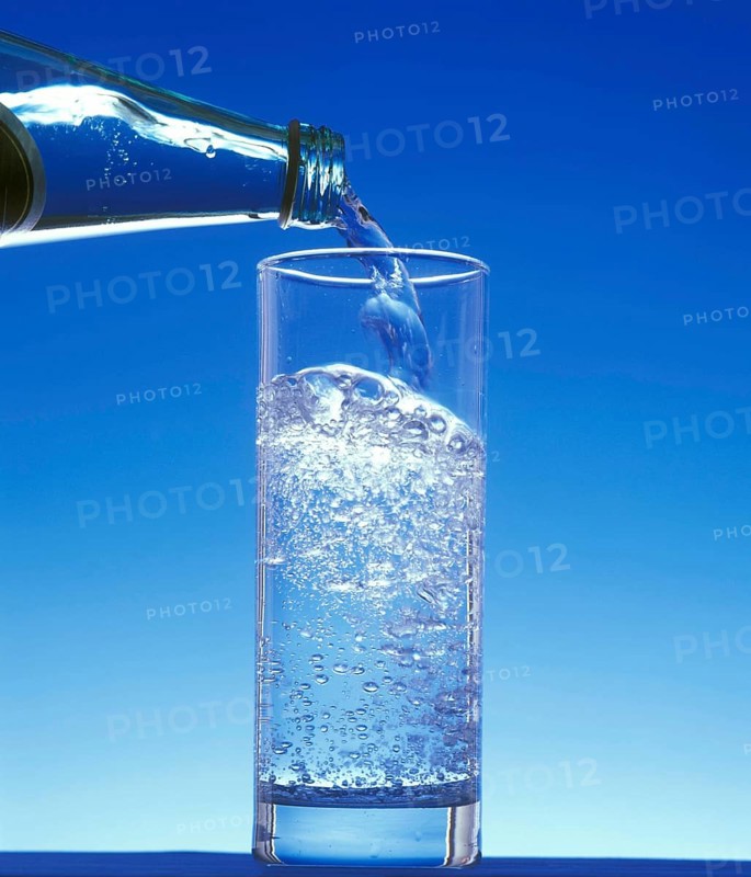Sparkling Water being Poured in a Glass against Blue Background