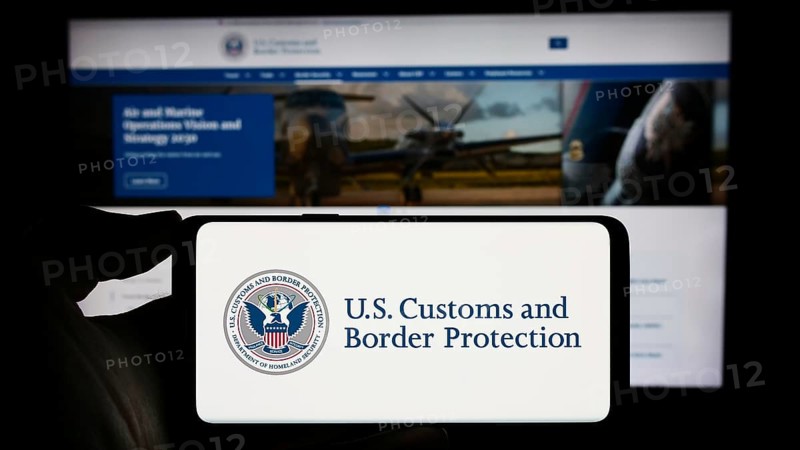 Stuttgart, Germany, 10-29-2023: Person holding mobile phone with seal of agency United States Customs and Border Protection (CBP) in front of web page. Focus on phone display, Europe