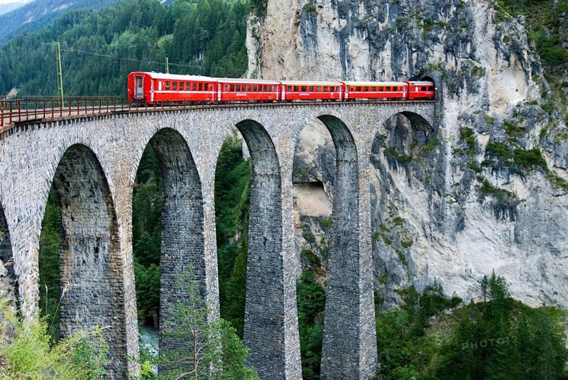 Red train of swiss Rhätische Bahn, Rhaetian Railway Company or Glacier Express on Viaduct Landwasserviadukt, near town of Filisur, Grisons, Switzerland, Europe