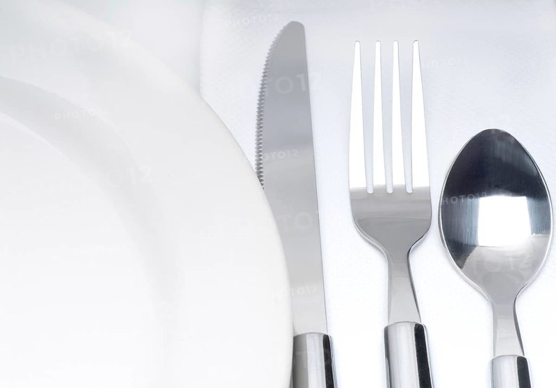 Close up of a cutlery set on a table with napkin and dish
