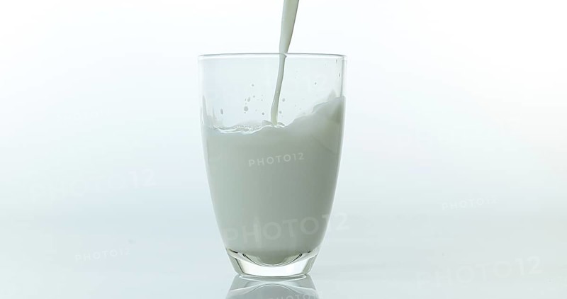 Milk being poured into Glass against White Background