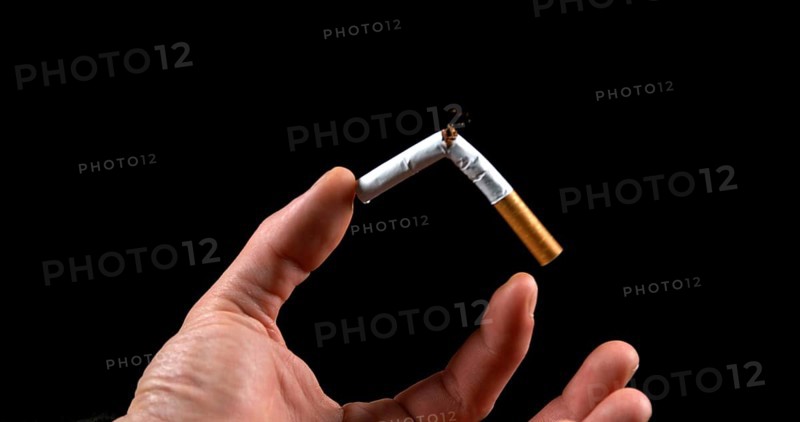 Hand of Man who breaks a Cigarette on Black Background