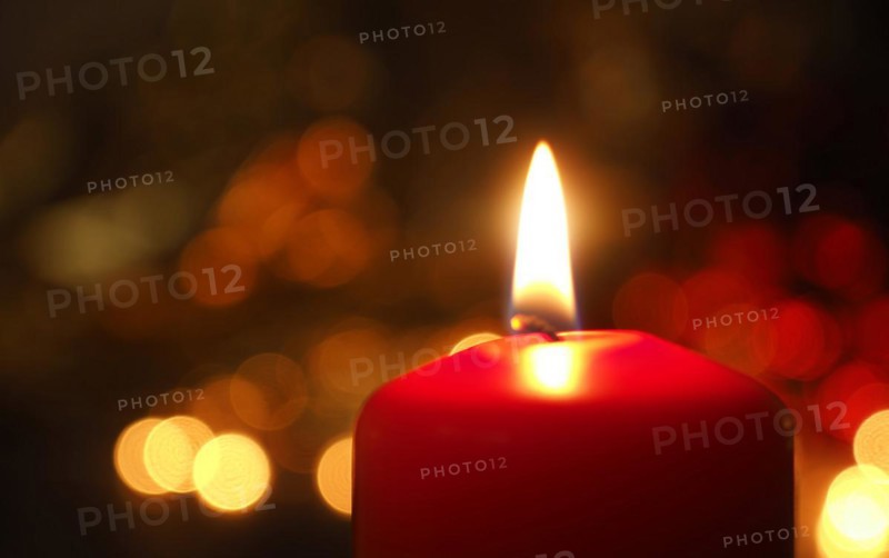 First Advent candle burning with Christmas decoration on a wooden table