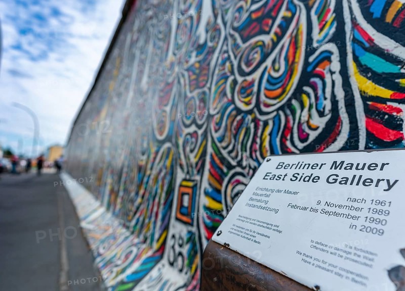 Berlin, Germany - 25 August 2020: view of a mural on the Berlin Wall at the famous East Side Gallery with information plaque