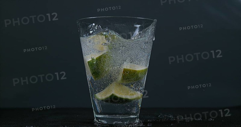 Green Citrus (citrus aurantifolia), falling into a Glass of Water