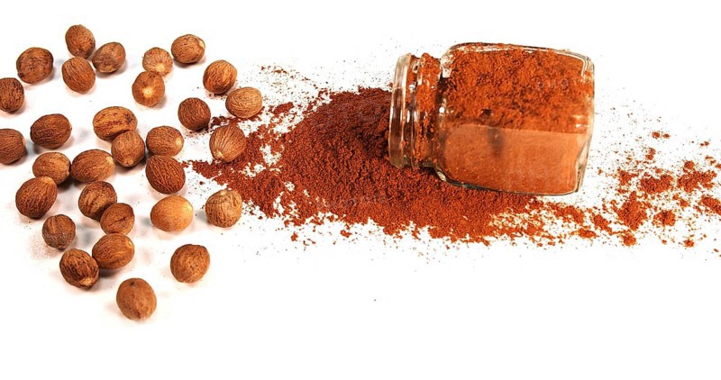 Nutmeg, myristica fragans, Nut falling on Nutmeg Powder against White Background