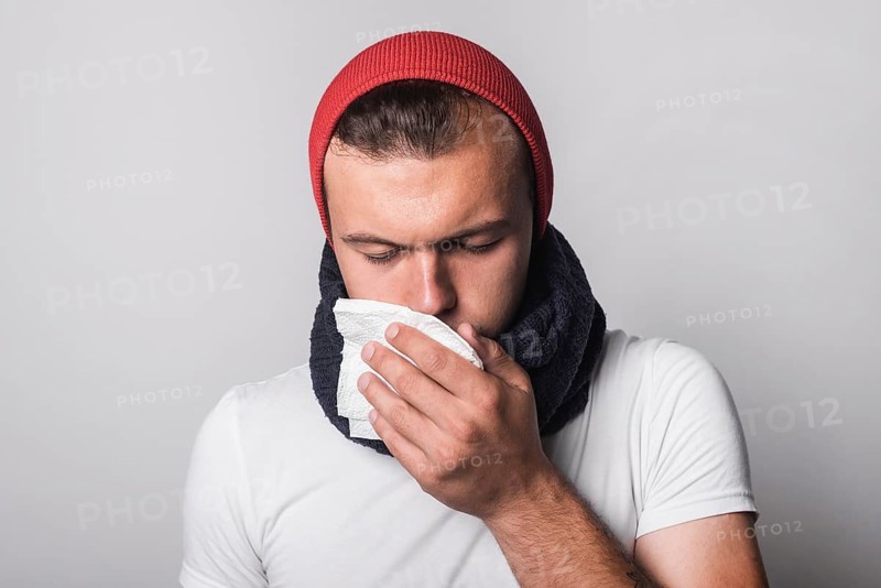 Young man suffering from cold flu against gray background