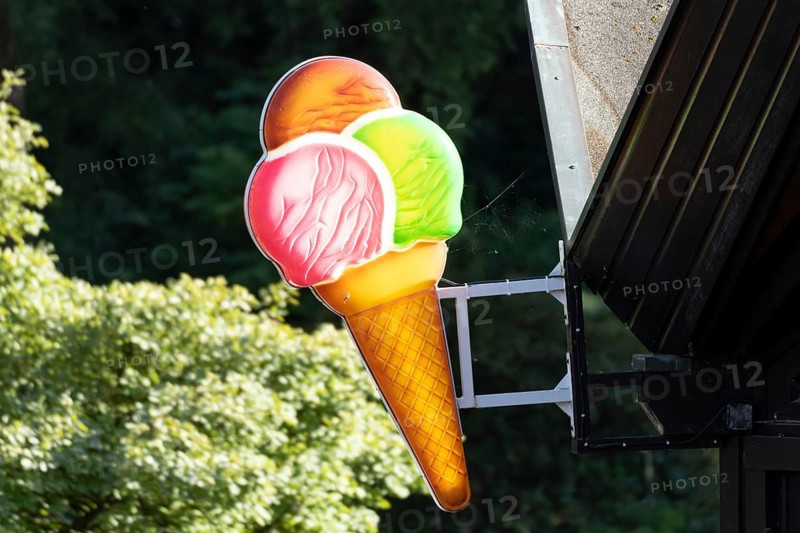 Illuminated sign in the shape of a colourful ice cream cone at an ice cream parlour in Planten un Blomen, Hamburg, Germany, Europe