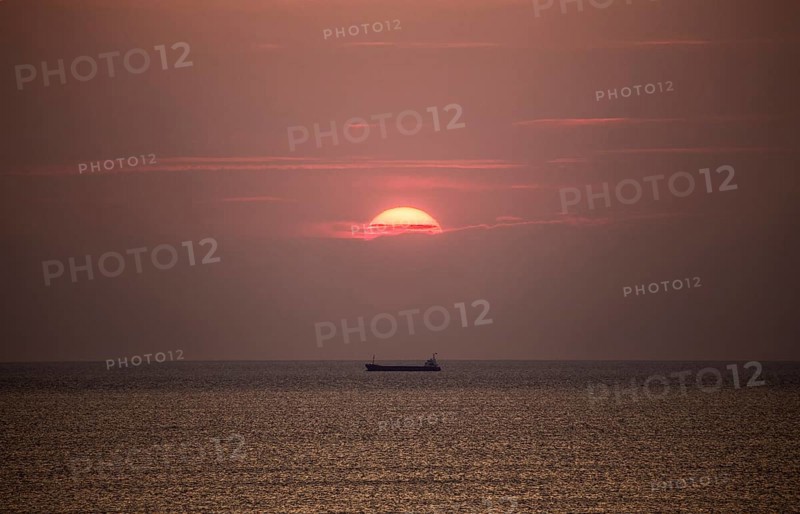 Cargo ship in the Mediterranean Sea under the evening sun, photographed from the beach near Tarragona, Catalonia, Spain, Europe