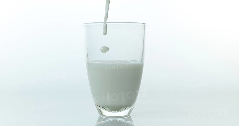 Milk being poured into Glass against White Background