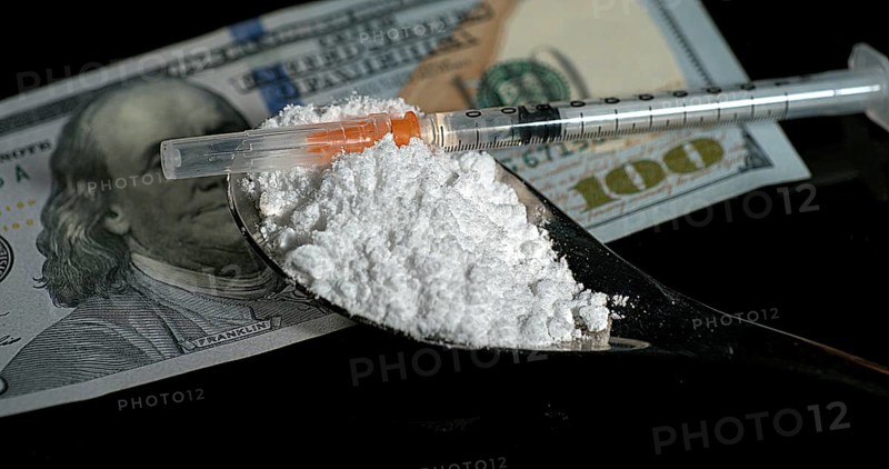 Dollar Bank notes and Siringa with Powder Drug against Black Background