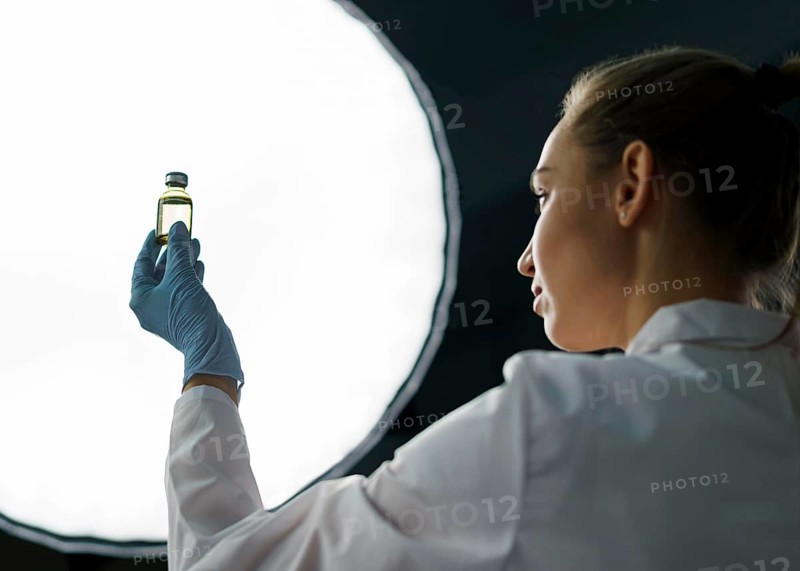 Female researcher laboratory holding vaccine bottle light
