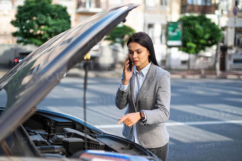 Businesswoman talking phone while her car broke down