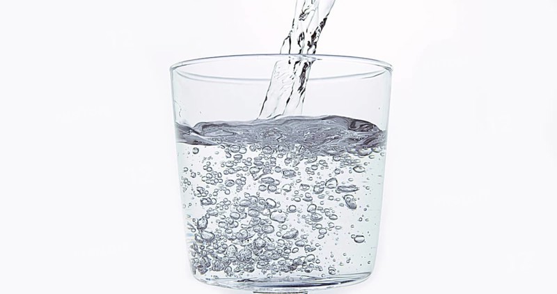 Water being poured into Glass against White Background