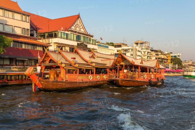 Ships at the pier for river cruise on a rice barge on the Chao Phraya river in Bangkok. Traditional rice barge, built for gastronomy on the river