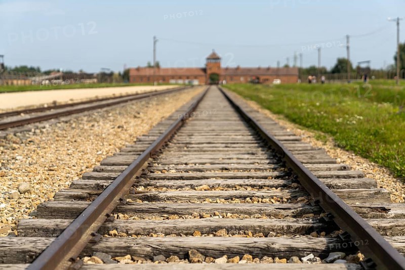 Auschwitz, Poland - 15 September, 2021: selective focus low angle view of the railroad tracks leading to the gatehouse at the Auschwitz concentration camp in Poland