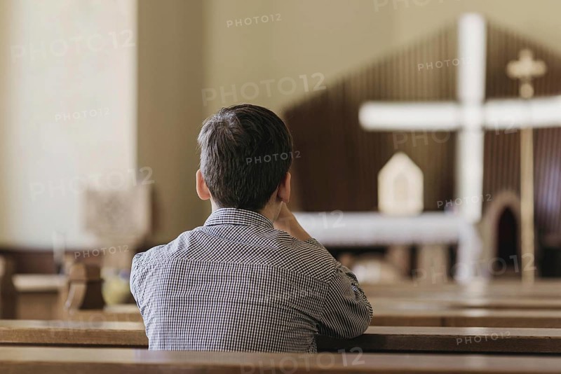 Back view young boy praying church. High resolution photo