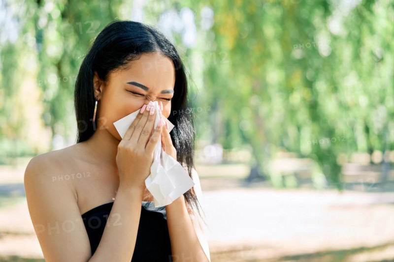 African american woman blows her nose into a tissue. allergy, disease, illness concept