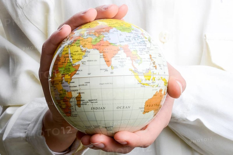 Child holding a small model globe in hand on white background