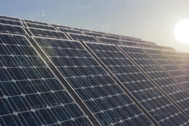 Solar power plant against the rising sun, selective focus on the first solar panel. Alternative energy concept, 3d rendering