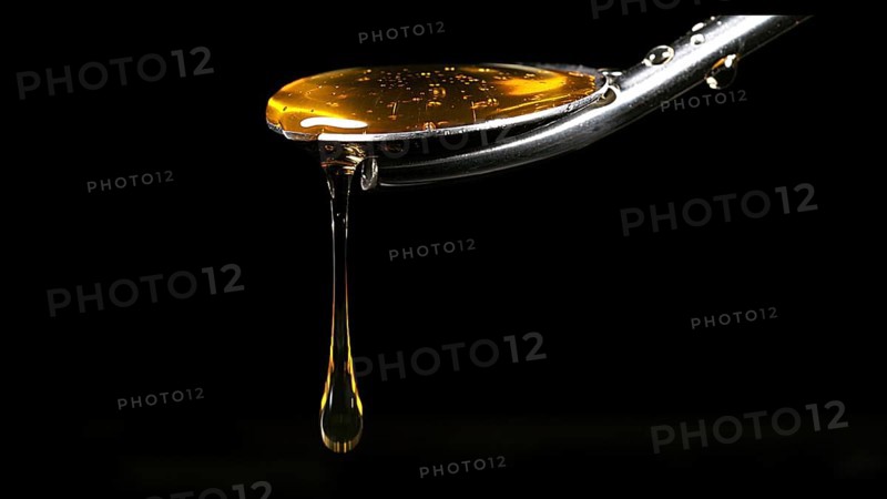 Honey Flowing from Spoon against Black Background
