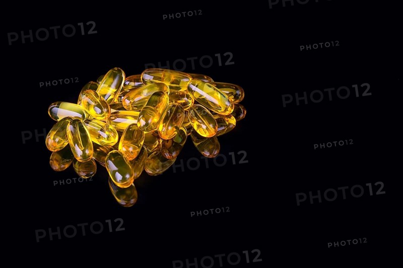 Capsules with fish oil on black background with reflection and copyspace