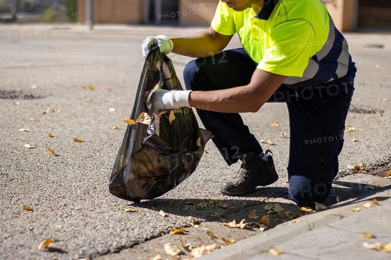 Unrecognizable latin street sweeper picking up leaves and garbage from the street floor