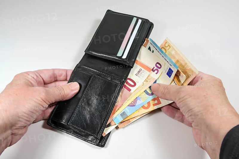Hands taking various euro banknotes out of a black leather wallet, money and finance concept, light gray background, selected focus, narrow depth of field