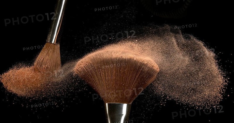 Make-up Brush spreading blush powder on black background