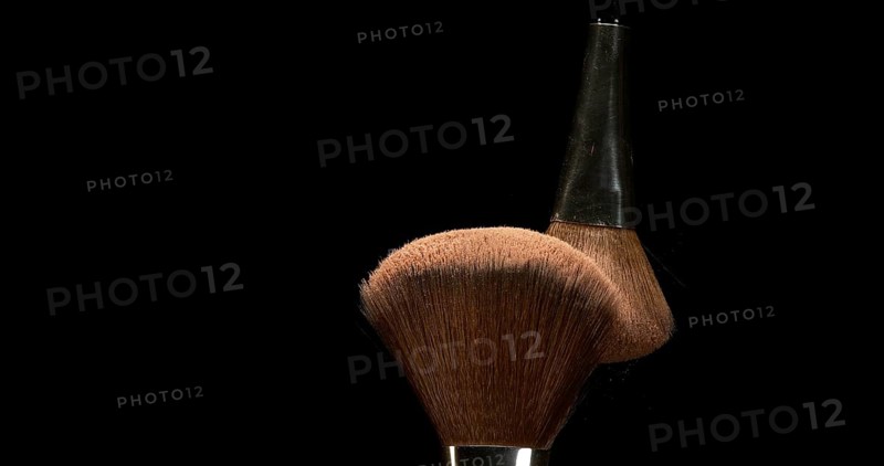 Make-up Brush spreading blush powder on black background