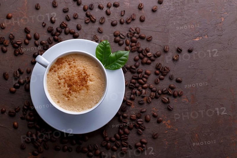 Cup of coffee cappuccino and coffee beans on the brown stone background